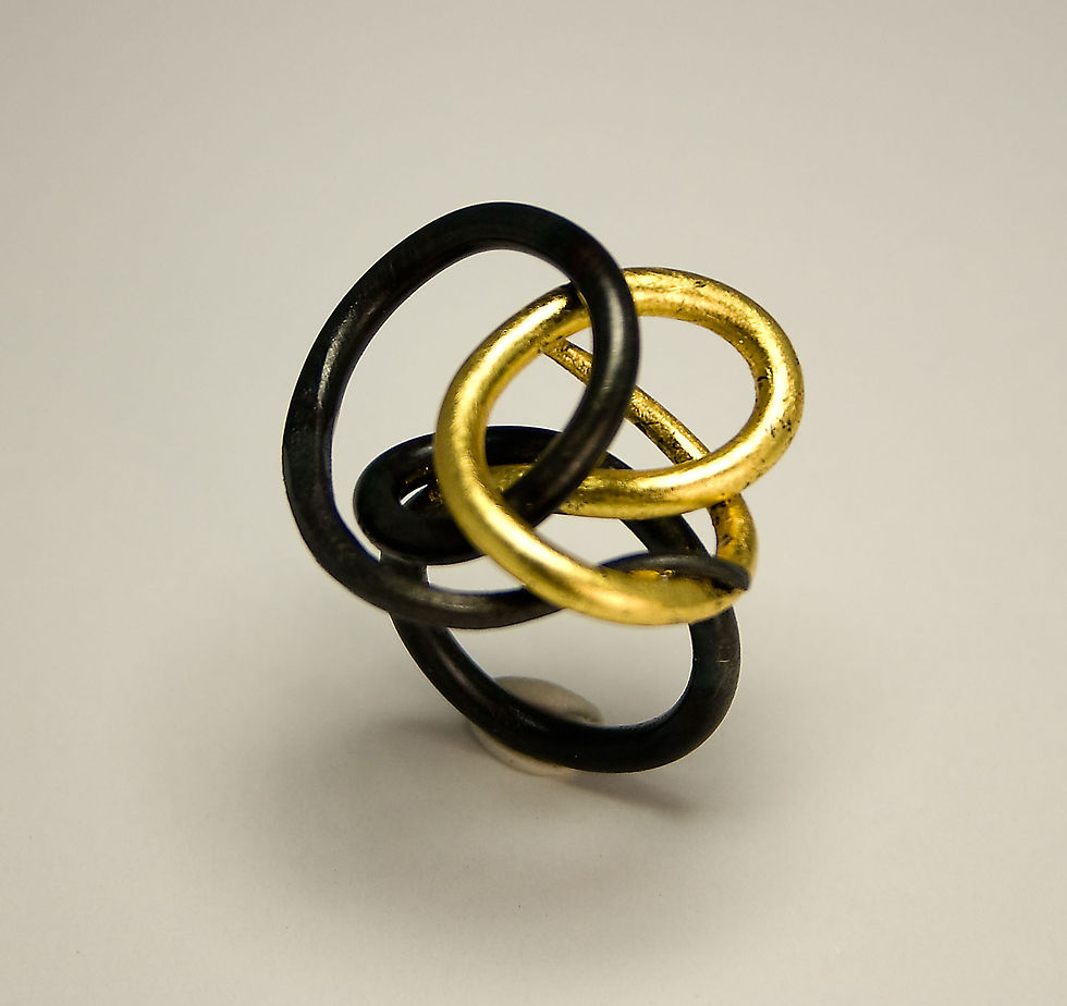 Statement ring with interlocked black, silver, and gold circles, contemporary and bold in mixed metals.