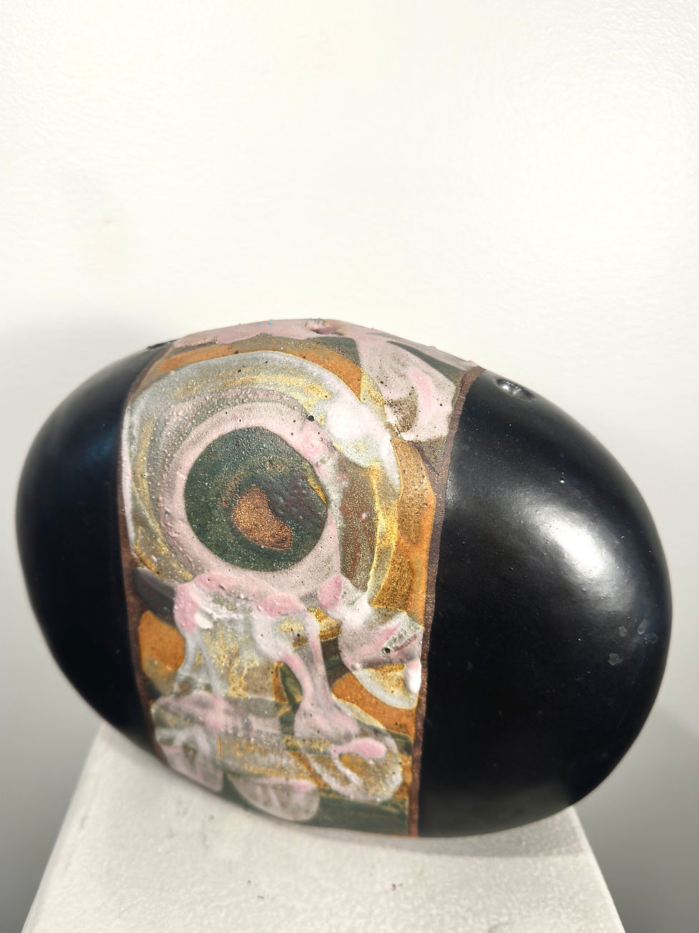 Split-glazed ceramic orb with smooth black surface on one side and a band of earthy abstract glaze on the other.

