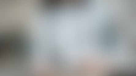 Woman in a hat smiles, holding white H and L letters with leaf designs against a background of decorative letters and words.