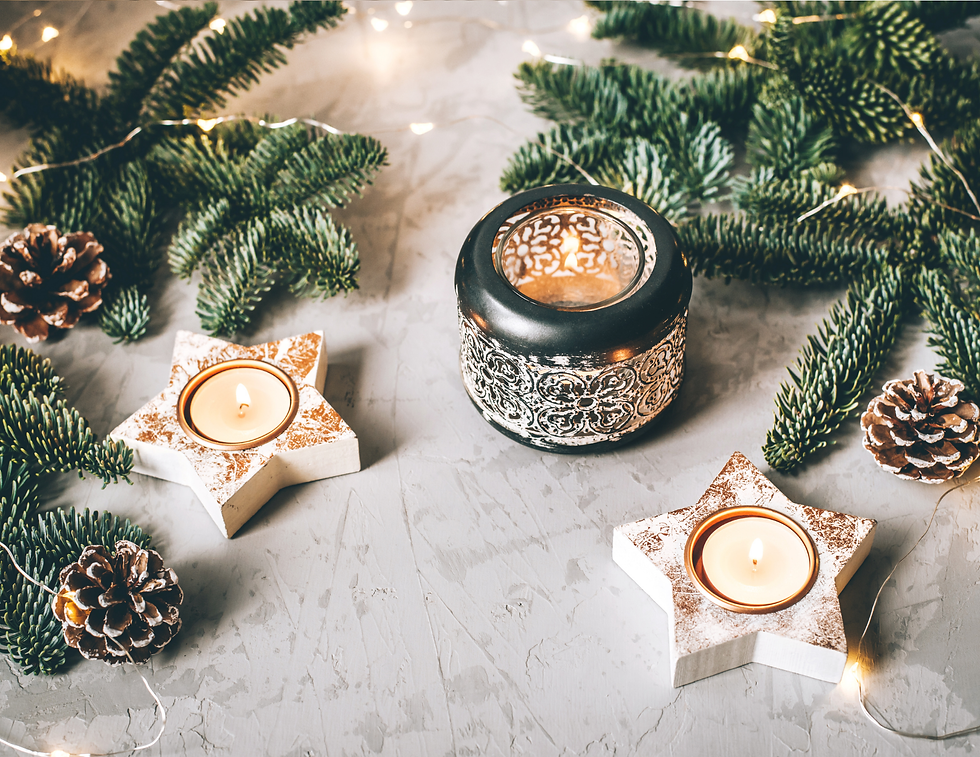 Star-shaped candle holders with lit candles, surrounded by pine branches and pinecones on a textured surface. Warm, cozy ambiance.