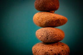 Pictures of stacked stones. The stones are orangish red. They are stacked in front of a blue wall.
