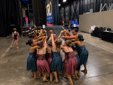 Young dancers gathering backstage in a supportive team circle before going on stage.