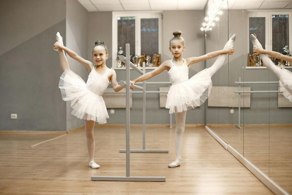 Two young ballet dancers practicing side leg extensions at the barre, showing strength and discipline in training.