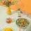 Thumbnail: Mellody Hot Plant-based Honey bottle next to salad bowl, yellow flower vase and glass of ice tea on a striped table cloth