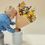 Thumbnail: A little blond boy in a denim shirt putting a multi-colored classic dried bouquet in a large vase