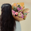 Thumbnail: The back of a woman with dark hair holding a pink classic dried bouquet over her shoulder