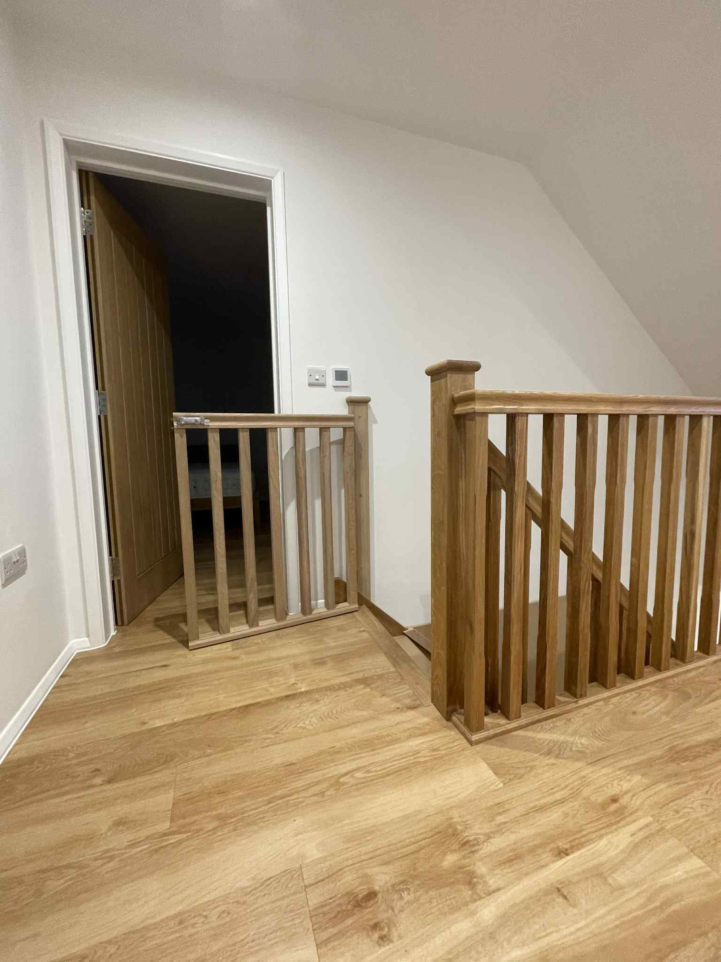 Custom baby gate installed at top of stairs, oak spindles to match the existing handrail