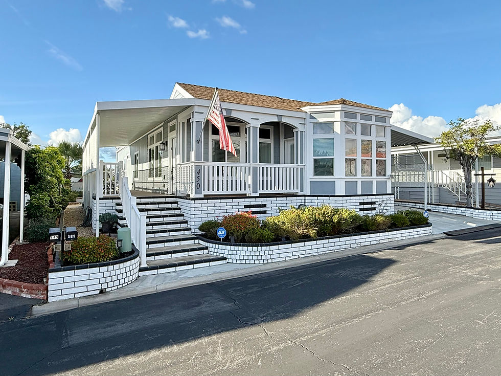 Eye-level view of a well-maintained manufactured home exterior with trimmed bushes
