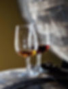 glass of white wine and a glass of red wine sitting on top of a wine barrel