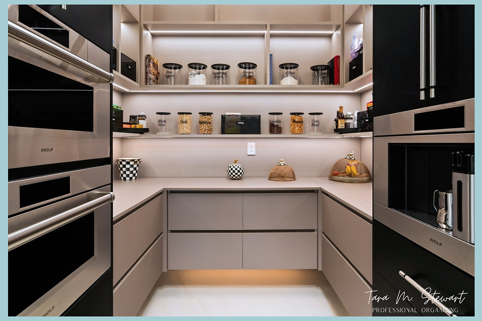 Full view of a luxury walk-in pantry with LED floating shelves, decanted canisters, and custom cabinetry framed by stainless steel Wolf wall ovens, organized by Tara M. Stewart Professional Organizing.