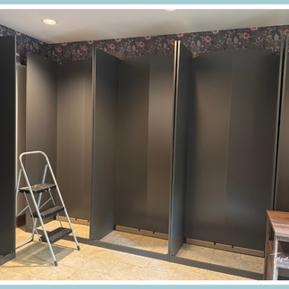 Installed IKEA PAX cabinet frames in a craft room, shown empty during installation with a step stool in front, highlighting the cabinet layout before shelving and organization are added.