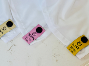 Three different colored snap-on sheet labels for Twin, Queen, and King size white linens on a marble countertop.