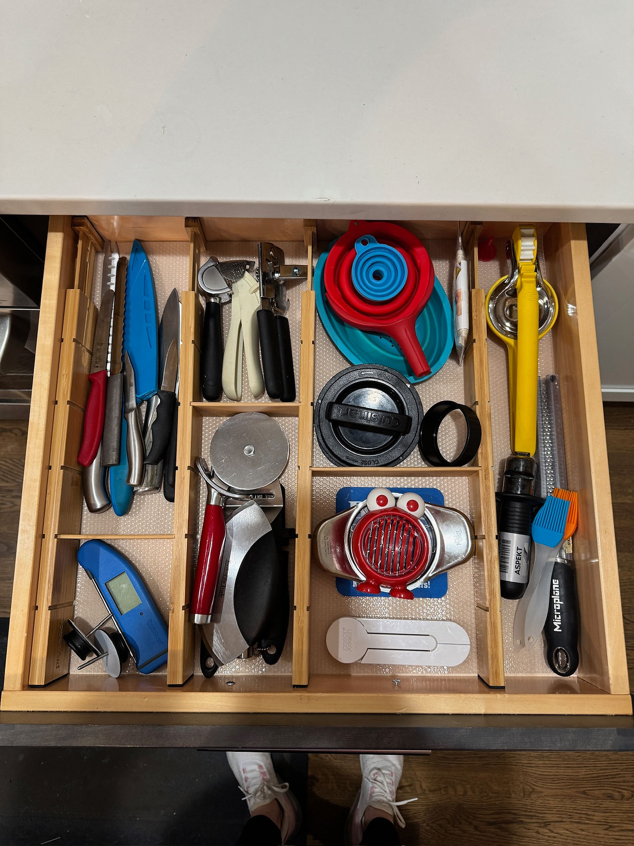 Open drawer with neatly organized compartments containing kitchen utensils. Wooden dividers.