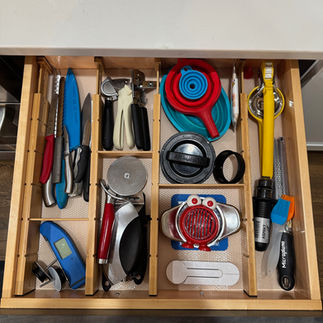 Open drawer with neatly organized compartments containing kitchen utensils. Wooden dividers.
