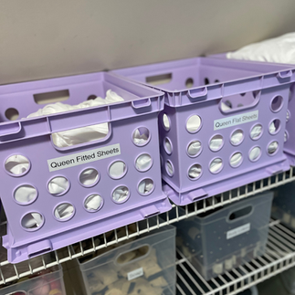 organized bed sheets in purple crates in an AirBnB