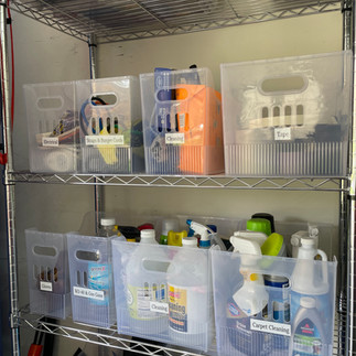 Wire shelving unit with clear labeled bins organizing household hardware and supplies, including categories like bathroom fixtures, electrical, bug killer, and rental miscellaneous.