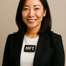 Asian woman in white blouse with black blazer wearing a tag that says MFT