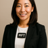 Asian woman in white blouse with black blazer wearing a tag that says MFT