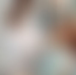 Dentist in white coat and mask examines patient in modern clinic. Patient wears a blue bib. Bright overhead light. Calm, clinical setting.