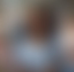 Smiling nurse in blue scrubs with a stethoscope stands in a hospital, surrounded by diverse, smiling colleagues. Bright, positive mood.