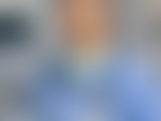 Chinese speaking CRNA smiling in blue scrubs with stethoscope