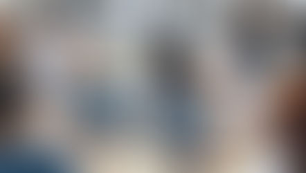 Medical professionals in white coats watch an online lecture on a screen. Laptops show medical images. Bright room with large windows.