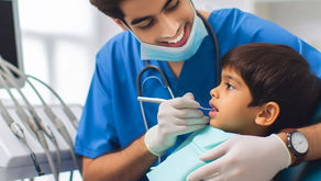 Dentist in blue scrubs and mask gently examines a young boy's teeth in a clinic, smiling. Bright, clean setting with dental equipment.