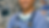 Smiling nurse in blue scrubs with stethoscope, arms crossed in an operating room. Surgical lights and equipment in the background.
