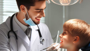 Dentist in white coat examines smiling boy under dental light. The boy wears a blue bib. Bright, clean clinic setting.