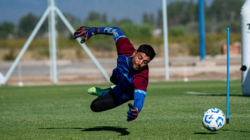 Goalkeeper diving to save a ball during intense soccer practice outdoors.