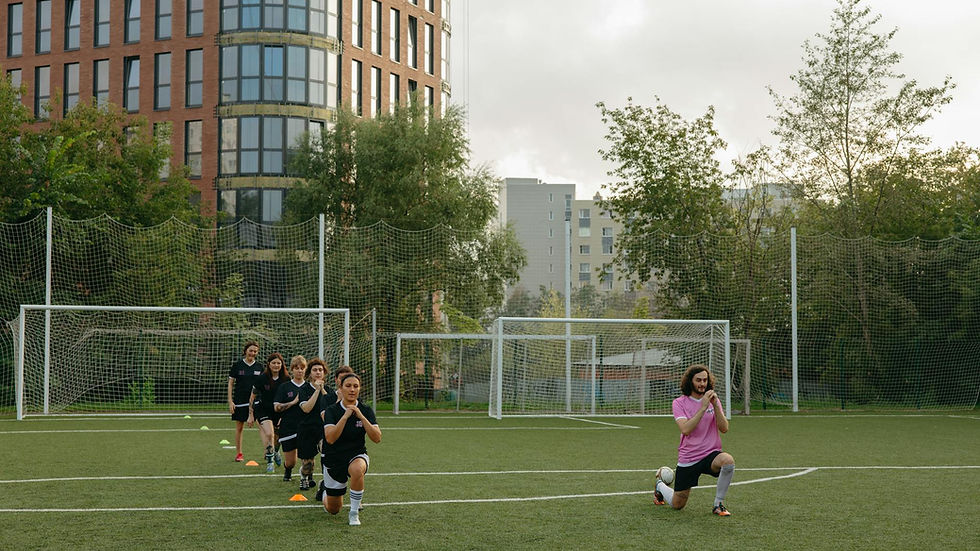 A group of kids performing warm-up exercises with their coach on a soccer field.