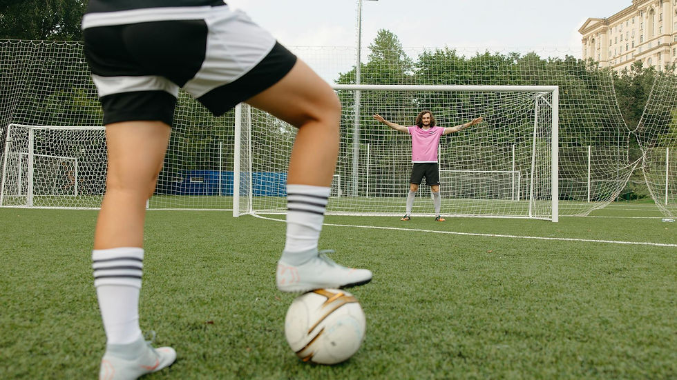 Soccer player in action aiming for the goal with a goalkeeper ready to defend.