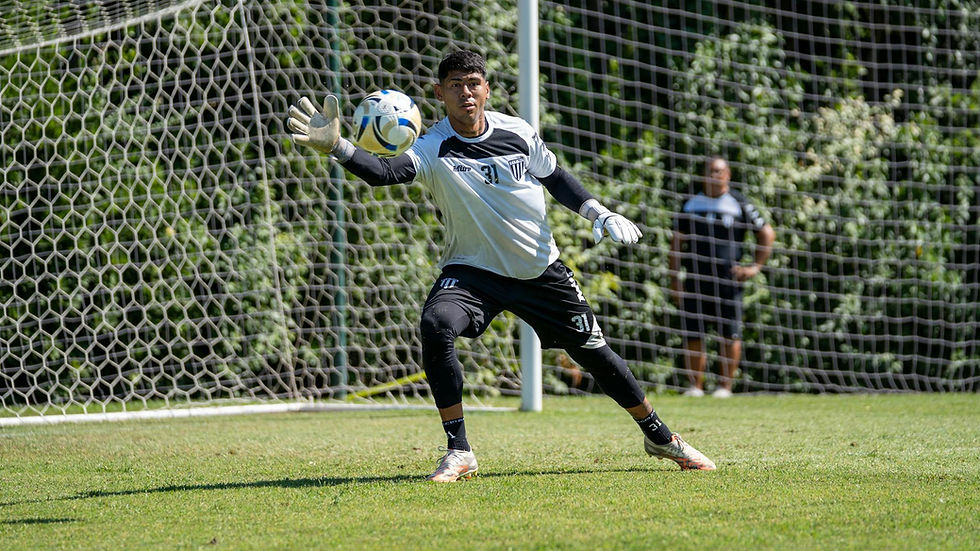 Focused goalkeeper during a training session at a sunny outdoor soccer field.