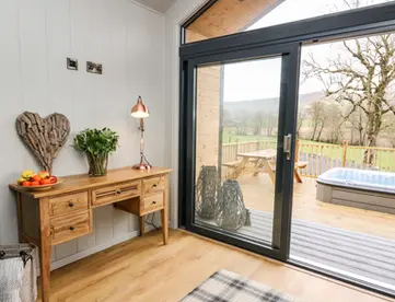 Inviting room, wooden desk, sliding door, deck with hot tub, rural view.