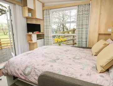 Double bed, television, window view of fenced green field.