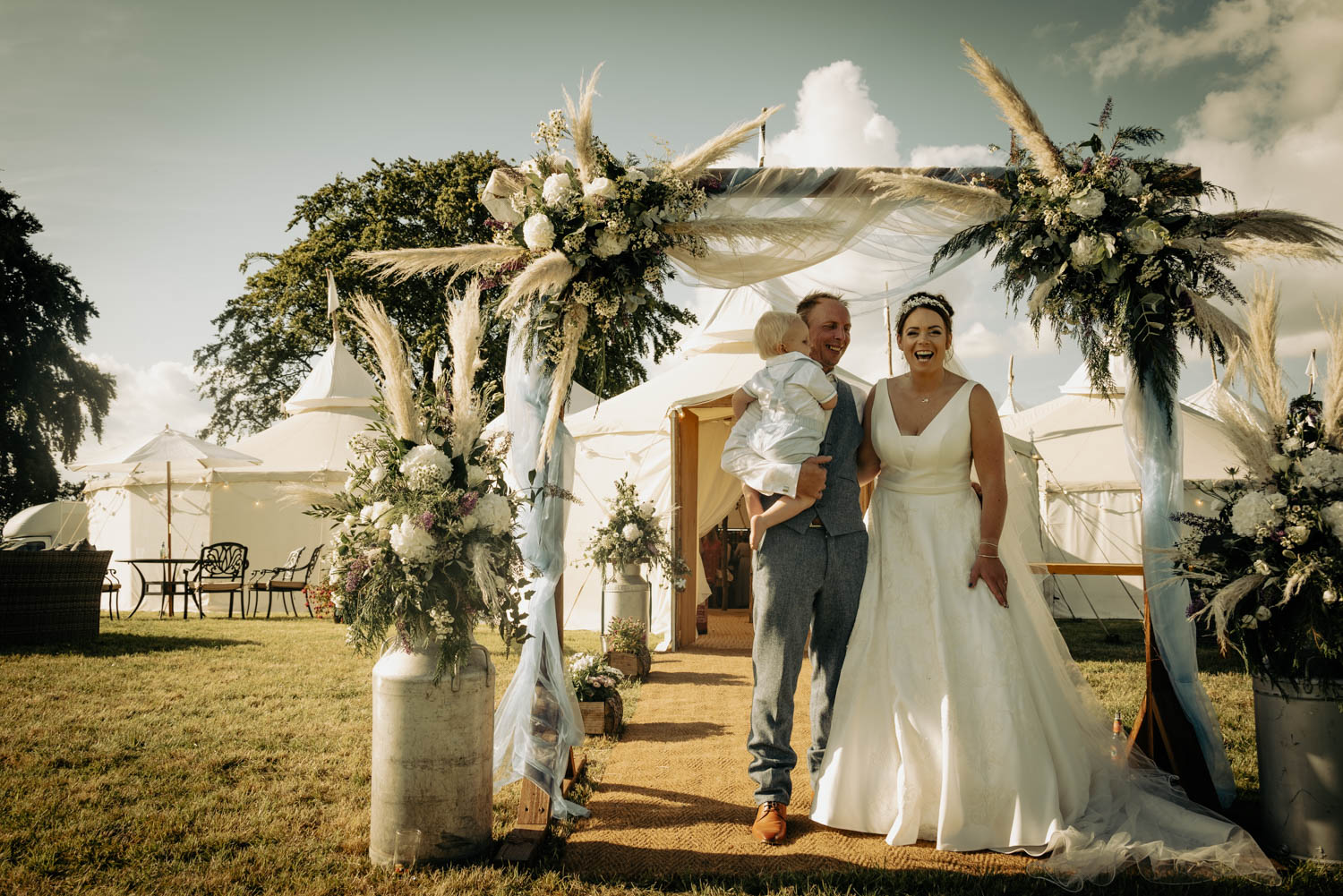 Happy couple with child, wedding ceremony, beautiful floral arch