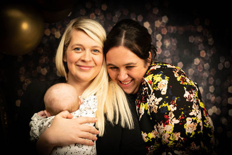Two women and a baby cuddle, smiling happily