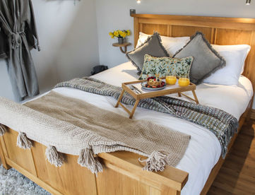 Cozy bedroom with wooden bed, breakfast tray, white duvet, tassel throw.