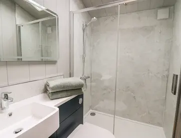 Modern bathroom with glass shower, white sink, toilet, and towels.
