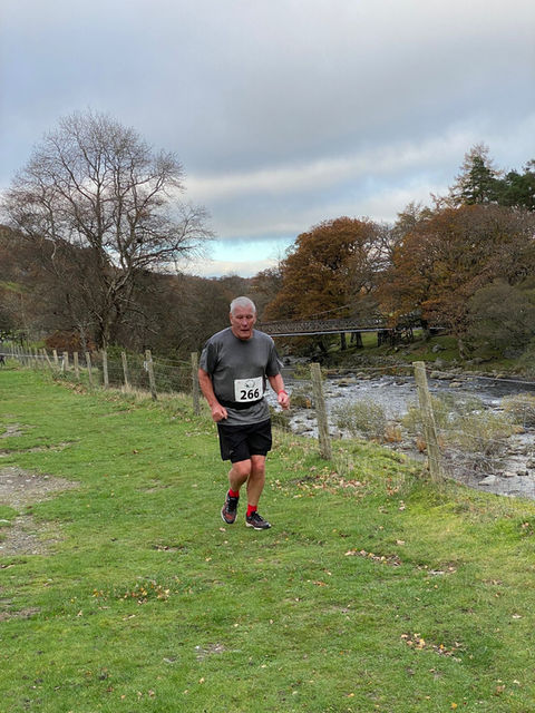 Runner, with bib, races along a pathway next to a river. Rhayader Running Club.
