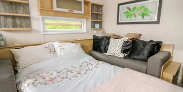 Cozy studio living space featuring bed, sofa, window, and floral bedding.