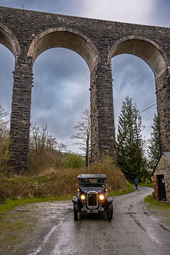 Vintage car parked beneath stone viaduct arches