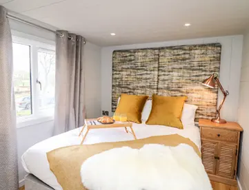 Cozy bedroom with white bed, yellow pillows, breakfast tray, and lamp.