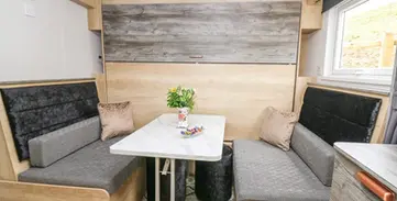 Cozy dining booth with cushioned seating, white table, and window.