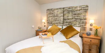 Cozy bedroom with double bed, breakfast tray, golden pillows, wooden nightstands.