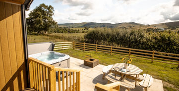 Outdoor patio with hot tub, picnic table, and scenic countryside view.