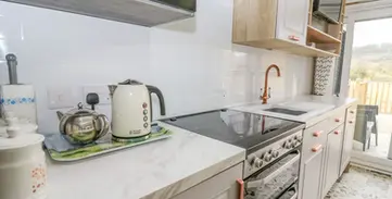 Bright, modern kitchen with white countertops, grey cabinets, stylish copper accents.