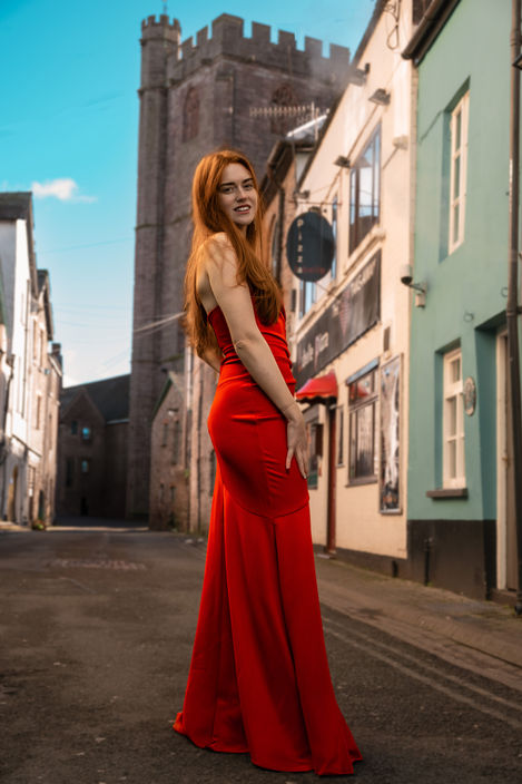 Woman in red gown smiles, city street background