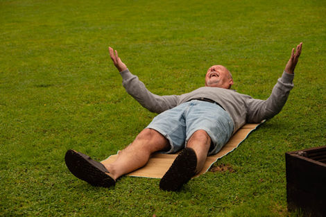 Man lying on cardboard on grass