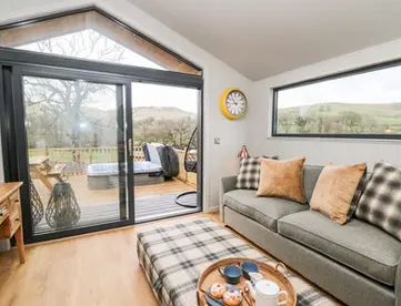 Modern living room, plaid ottoman, and outdoor deck with hot tub.